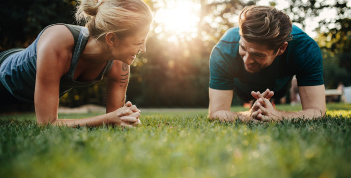 Fitness pár táhnoucí se venku v parku. Mladý muž a žena spolu cvičí ráno.