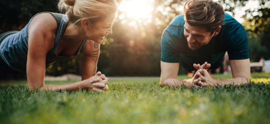 Fitness pár táhnoucí se venku v parku. Mladý muž a žena spolu cvičí ráno.
